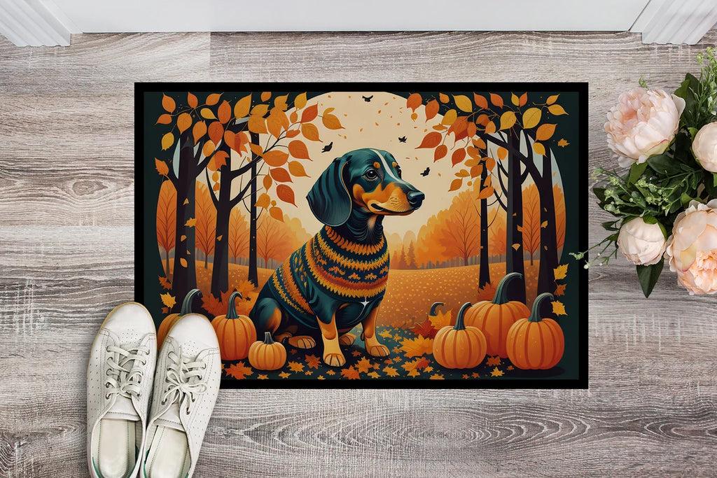 Decorative doormat with a dachshund in a sweater and pumpkins design on a wooden floor.