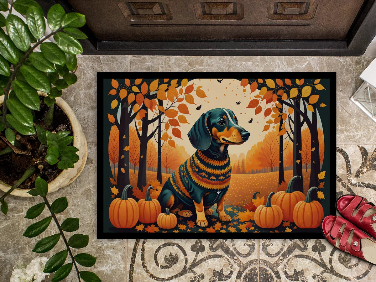 Decorative doormat with a dachshund in a sweater and pumpkins design on a patterned floor.