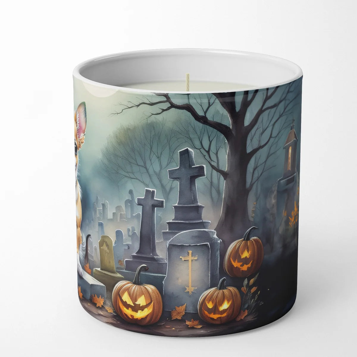 Candle with a Halloween-themed design featuring pumpkins, gravestones, and a tree on a white background.