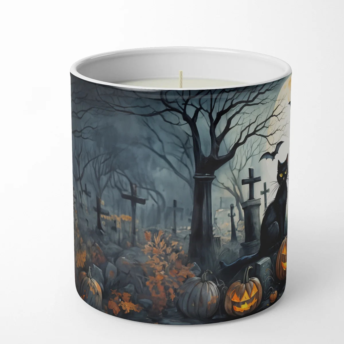 Candle with a Halloween-themed design featuring pumpkins, a cat, and tombstones on a white background.