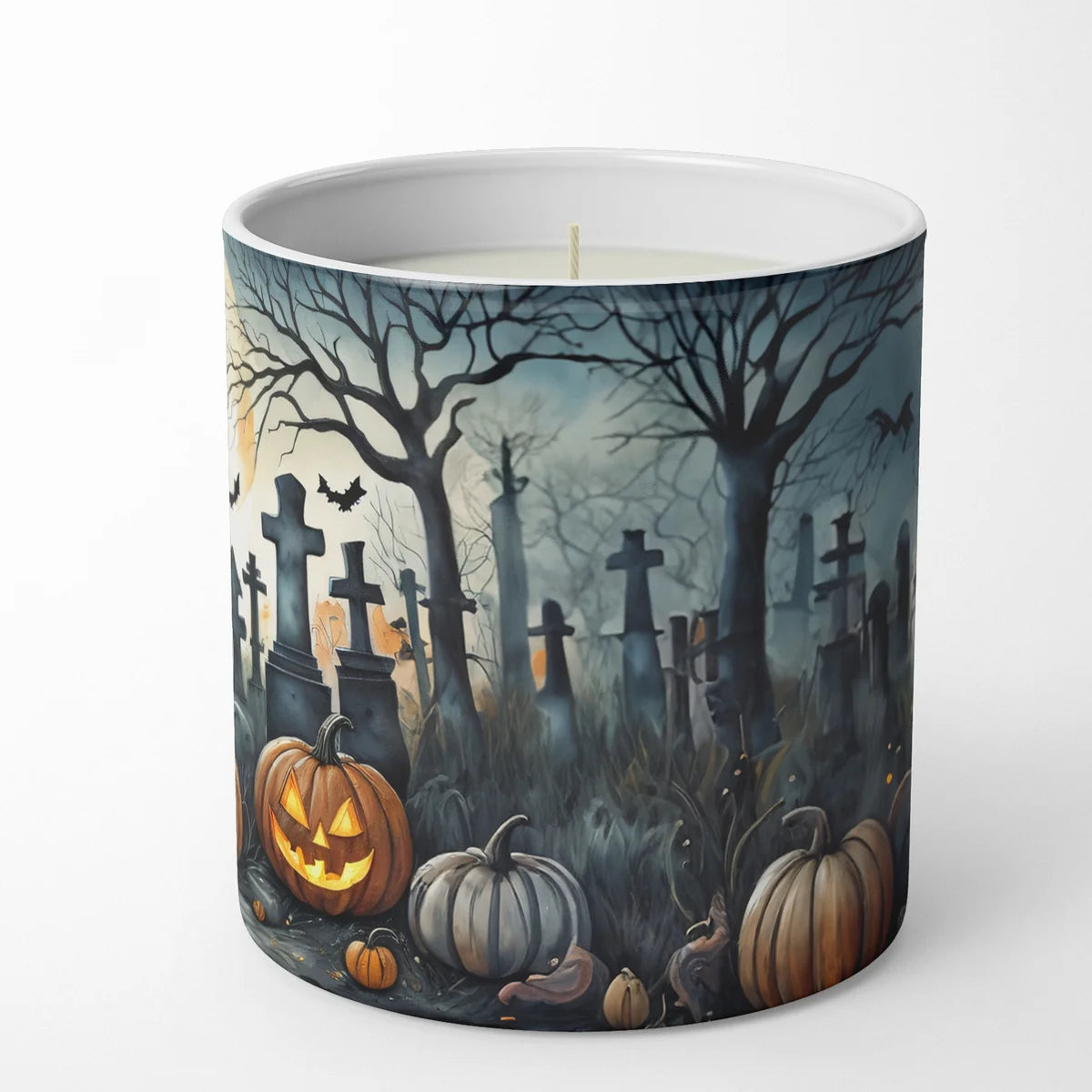A white ceramic candle jar featuring a detailed Halloween graveyard illustration with pumpkins, tombstones, bare trees, and bats, shown on a clean white background.