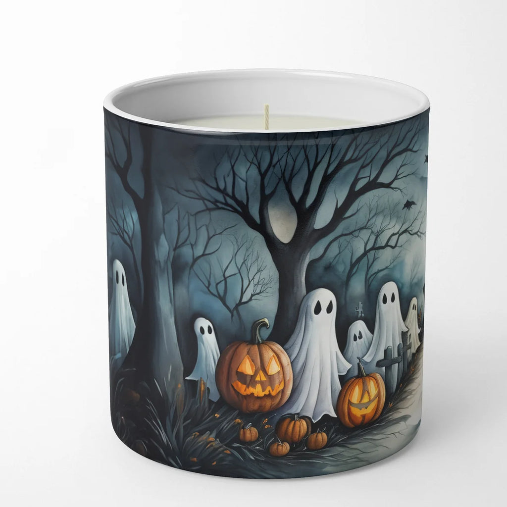 A white wax candle in a cylindrical ceramic mug with a Halloween-themed illustration on the outside. The design features spooky bare trees, glowing jack-o'-lantern pumpkins, and white ghosts in a dark blue night sky.