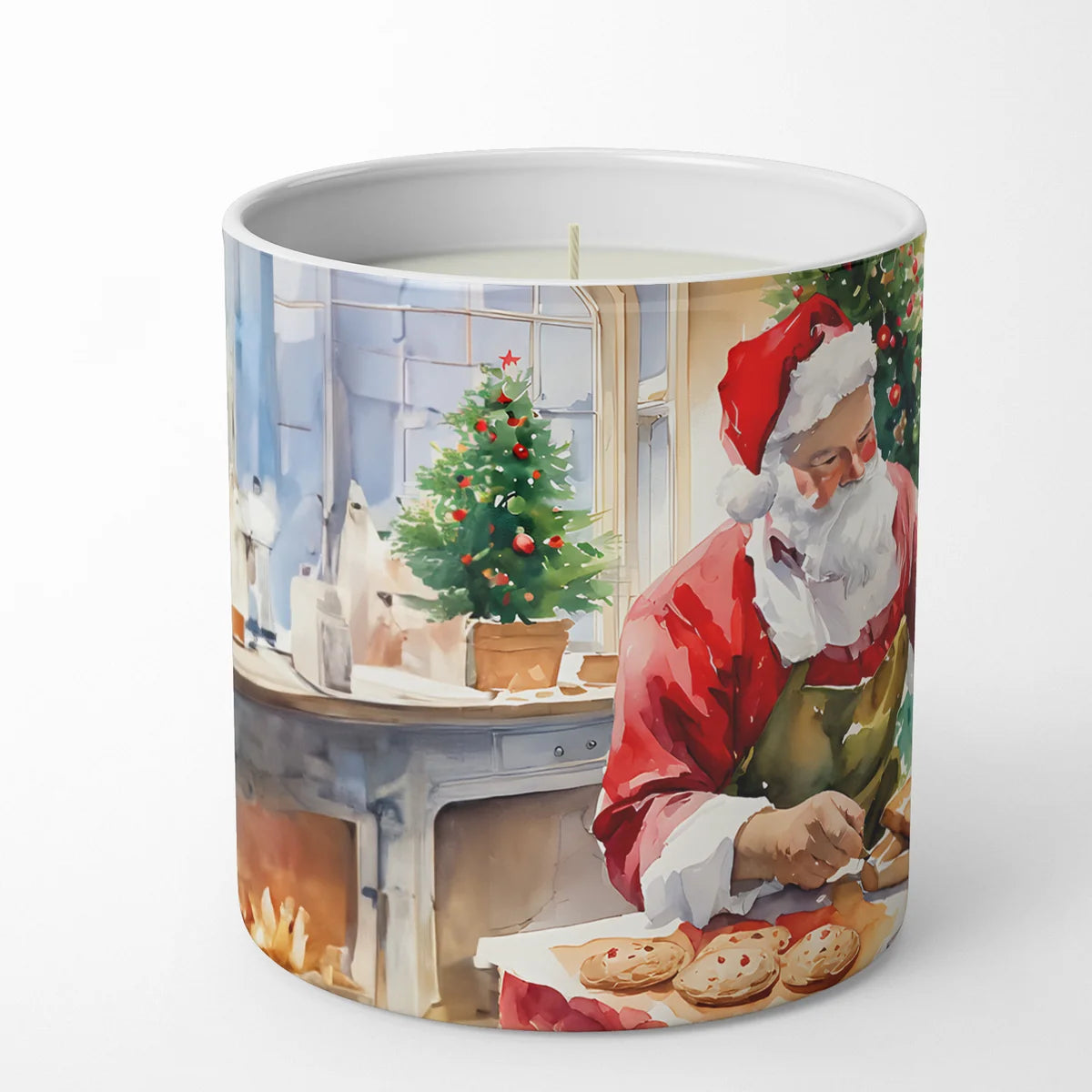 A cylindrical candle with a printed watercolor illustration of Santa Claus baking cookies by a fireplace, shown on a clean white background.