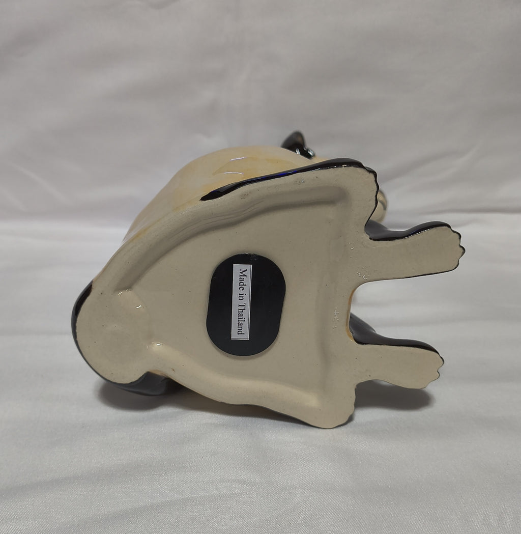 A ceramic bank, shown from the bottom to reveal a cream-colored glazed base with a black rubber stopper