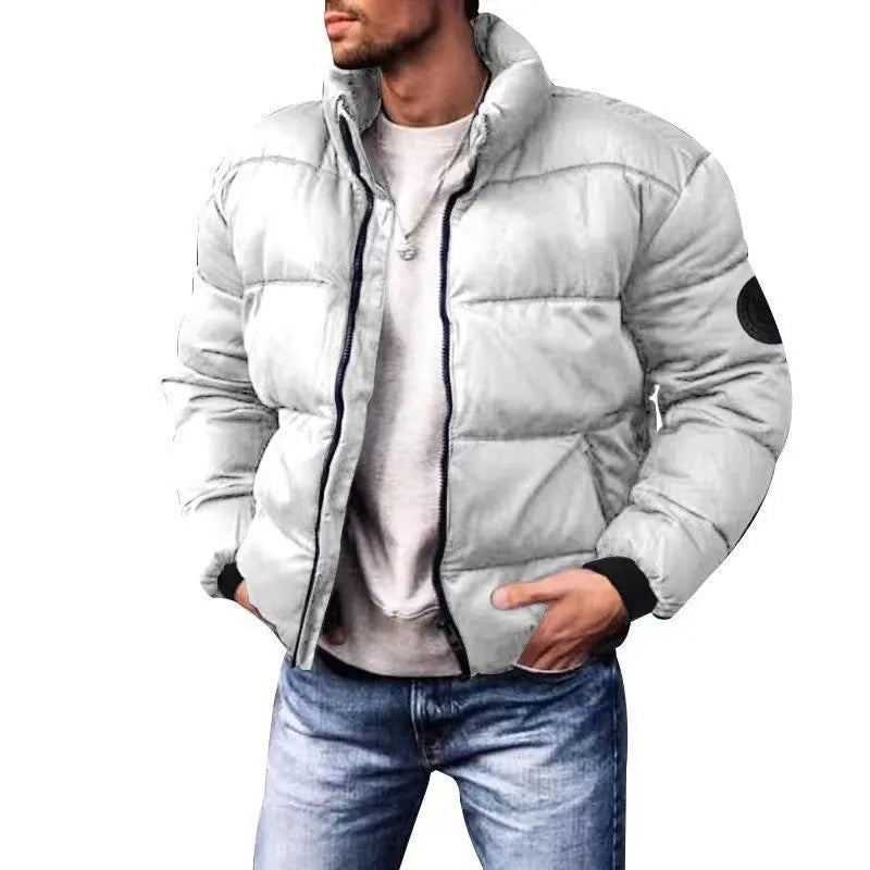Man wearing a light gray puffer jacket with a white shirt and blue jeans on a white background