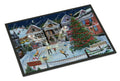A rectangular doormat with a black border featuring a detailed winter village scene. The illustration shows snow-covered houses, a decorated Christmas tree, people ice skating in a town square, and a dark night sky with a crescent moon.