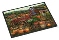 A rectangular doormat with a black border featuring a detailed autumn farm scene. The design shows a red barn, a rustic red wagon loaded with pumpkins, several orange pumpkins scattered on the ground, baskets of produce, a cat, and rolling hills in the background.