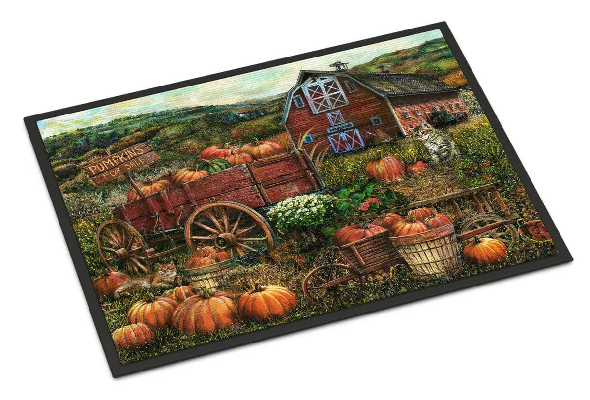 A rectangular doormat with a black border featuring a detailed autumn farm scene. The design shows a red barn, a rustic red wagon loaded with pumpkins, several orange pumpkins scattered on the ground, baskets of produce, a cat, and rolling hills in the background.