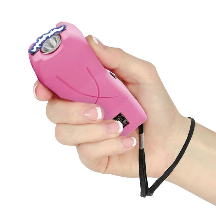 Pink stun gun device held in a hand on a white background