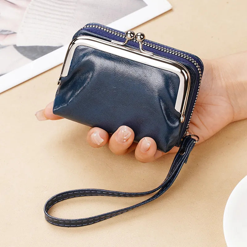 Hand holding a navy blue clutch with a strap on a beige surface