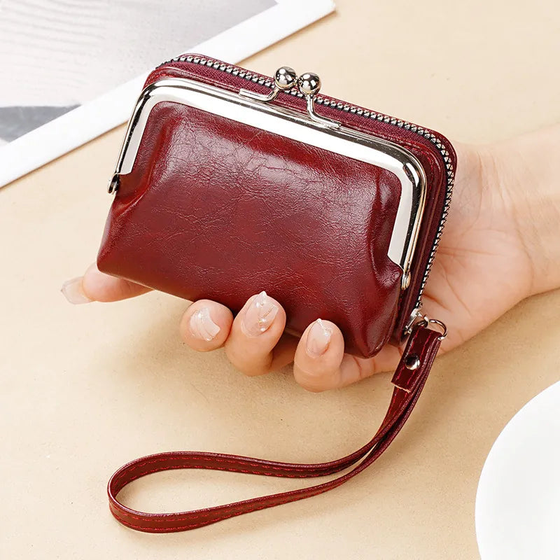 Red leather wallet with a strap held by a hand on a light background