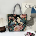 Tote bag with floral and bird design on a surface with a magazine and small lamp.