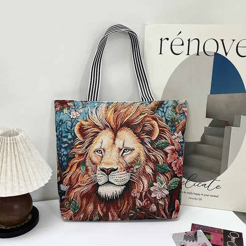 Tote bag with a lion design on a surface with a magazine and lamp in the background