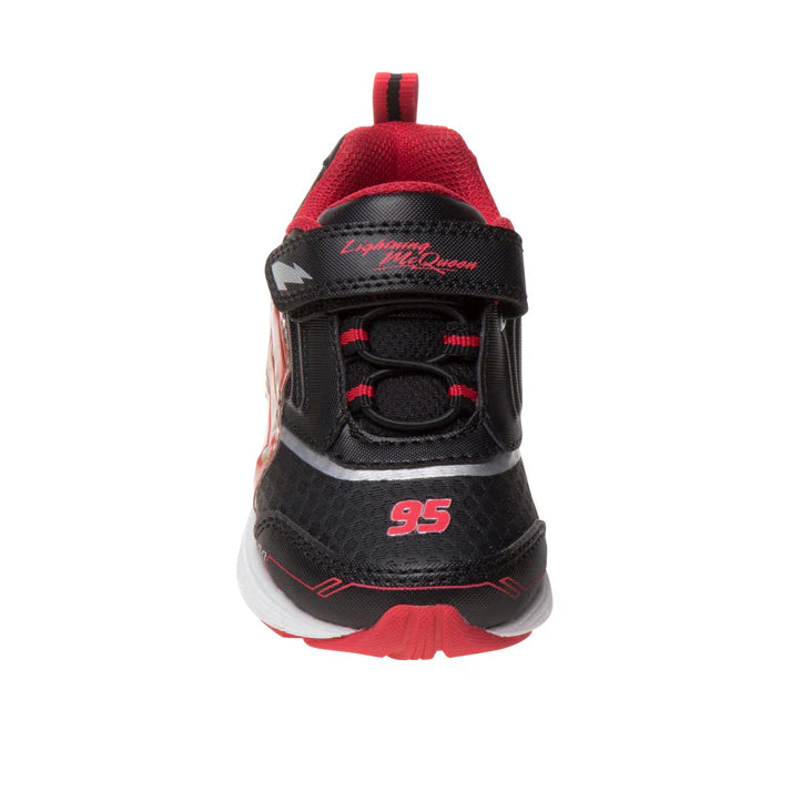 A black and red children's athletic sneaker shown from the front, featuring a hook-and-loop strap closure with 'Lightning McQueen' text, a red '95' on the toe, and a red pull tab on a white background.
